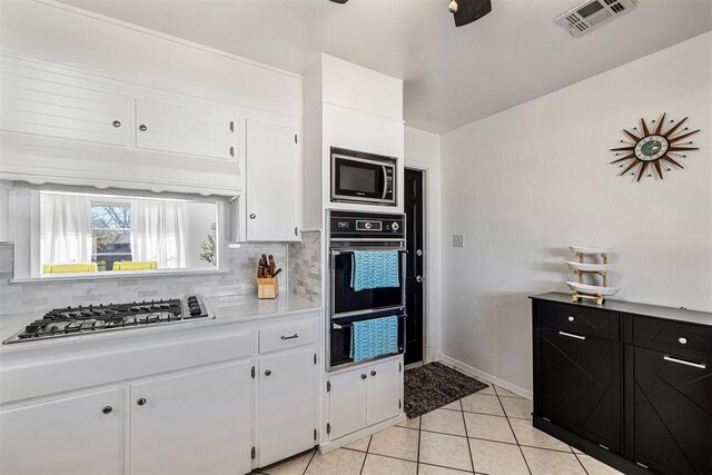 kitchen featuring white cabinets, decorative backsplash, light tile patterned floors, and stainless steel appliances