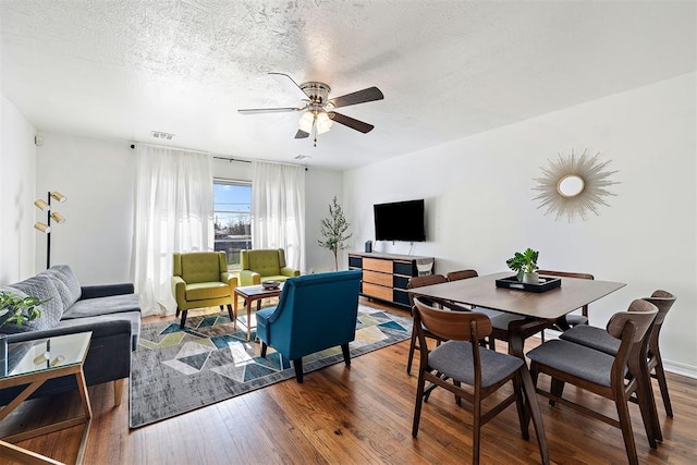 living room featuring a textured ceiling, ceiling fan, and dark wood-type flooring