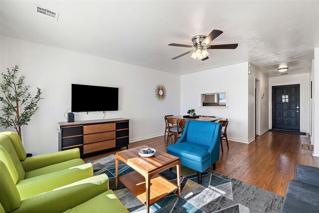 living room with ceiling fan and dark hardwood / wood-style flooring