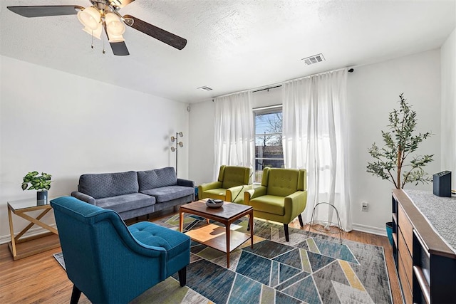 living room featuring ceiling fan, dark wood-type flooring, and a textured ceiling