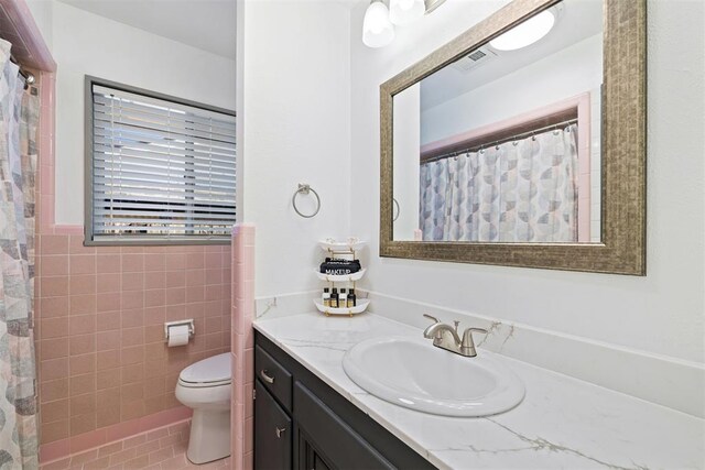 bathroom with vanity, tile patterned floors, a shower with curtain, toilet, and tile walls