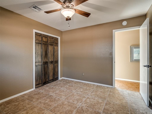 unfurnished bedroom with baseboards, visible vents, ceiling fan, and a closet