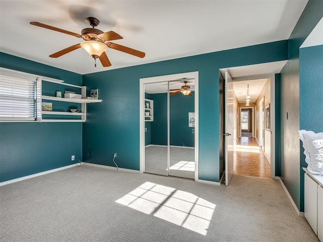 unfurnished bedroom with a closet, light colored carpet, ceiling fan, and baseboards