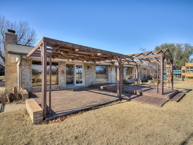 rear view of property featuring brick siding, a chimney, a wooden deck, and a pergola