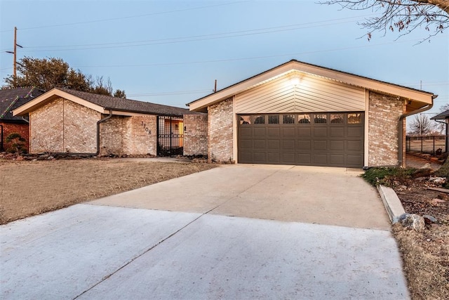 view of front of property featuring driveway, fence, and brick siding