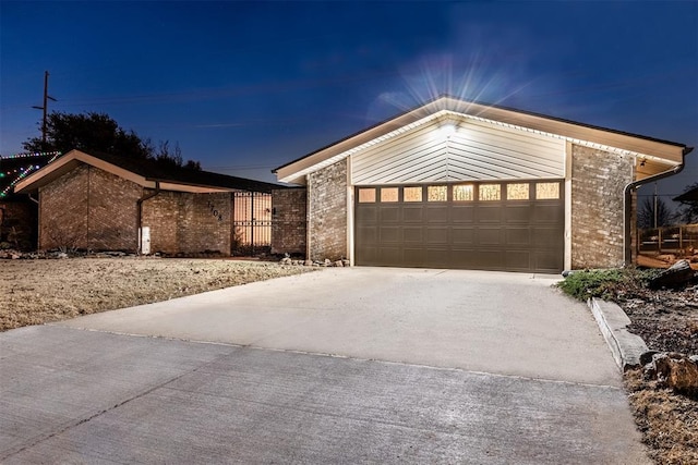 view of front of house featuring an attached garage, concrete driveway, and brick siding