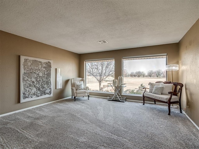 sitting room featuring a textured ceiling, a textured wall, carpet floors, visible vents, and baseboards