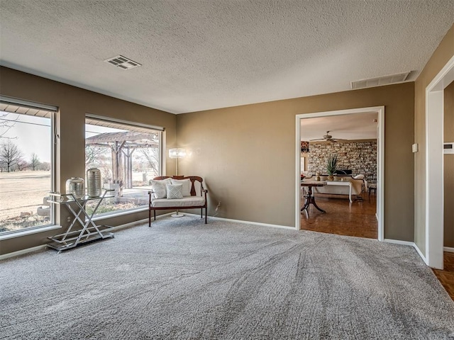 unfurnished room with carpet flooring, visible vents, baseboards, and a textured ceiling