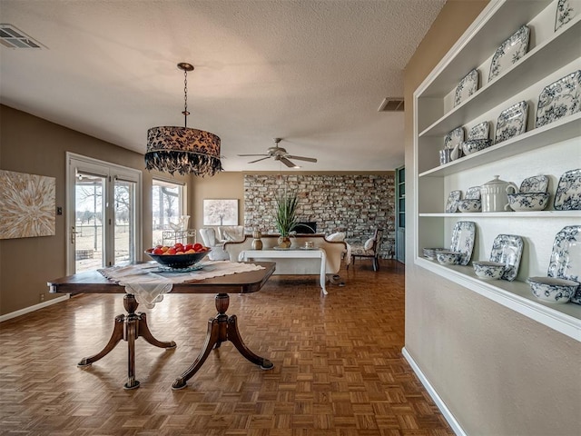 dining room featuring a textured ceiling, built in shelves, visible vents, and baseboards