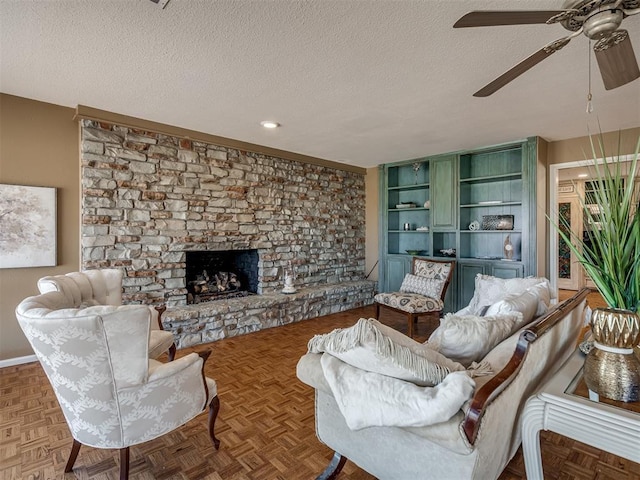 living area with a ceiling fan, a fireplace with raised hearth, a textured ceiling, and baseboards