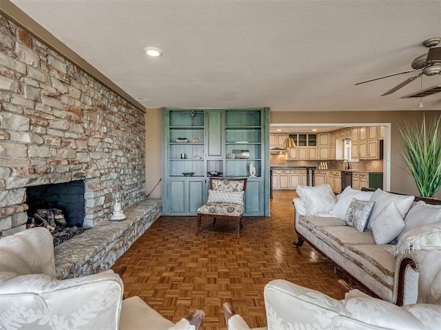 living room featuring a ceiling fan, visible vents, a fireplace, and a textured ceiling