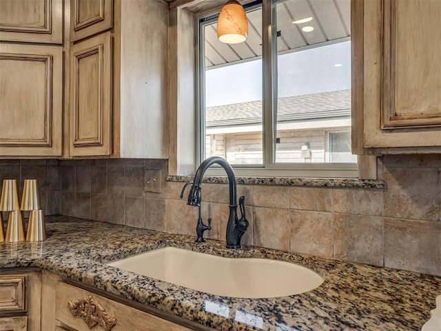 kitchen with dark stone countertops, a sink, and decorative backsplash