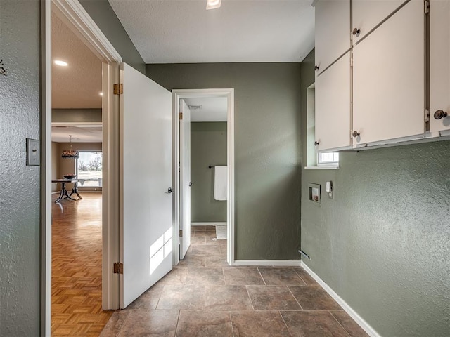 hall with a textured wall and baseboards