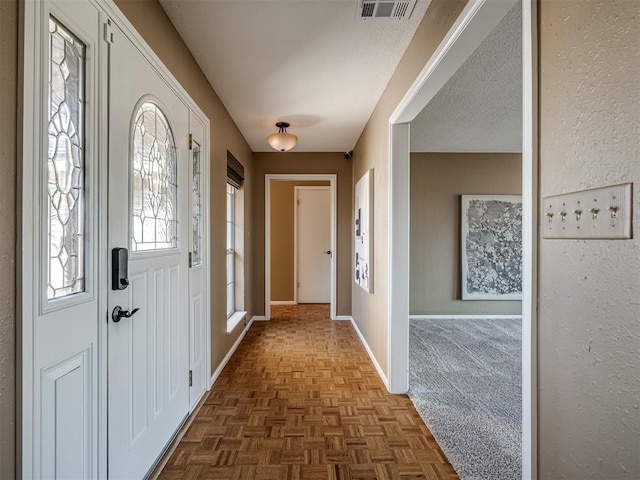 entrance foyer featuring visible vents, baseboards, and a textured ceiling