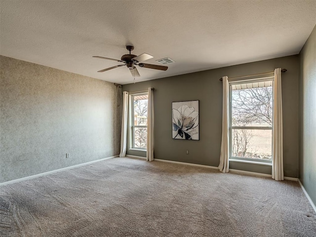 empty room with a ceiling fan, visible vents, a textured ceiling, and light colored carpet