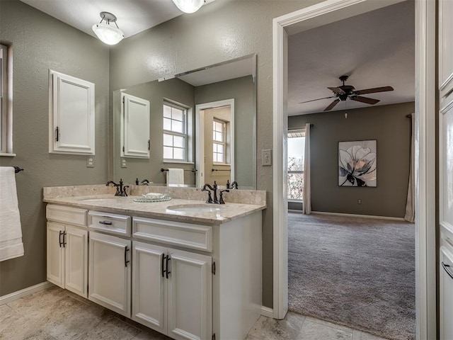 full bathroom featuring a textured wall, double vanity, a sink, and a ceiling fan