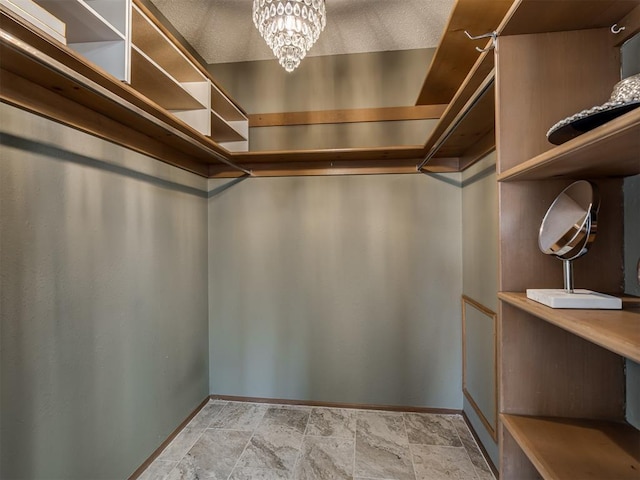 spacious closet featuring stone finish floor and a notable chandelier