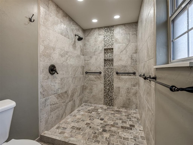 bathroom with toilet, a tile shower, and recessed lighting