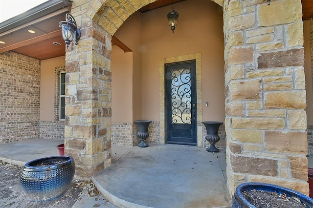 doorway to property featuring stone siding and brick siding