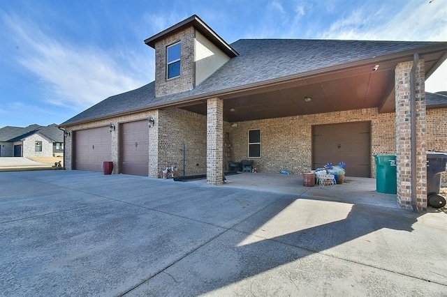 view of front of property with concrete driveway, brick siding, and a shingled roof