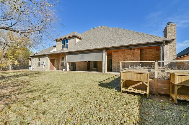 rear view of house with a yard, a shingled roof, fence, and brick siding