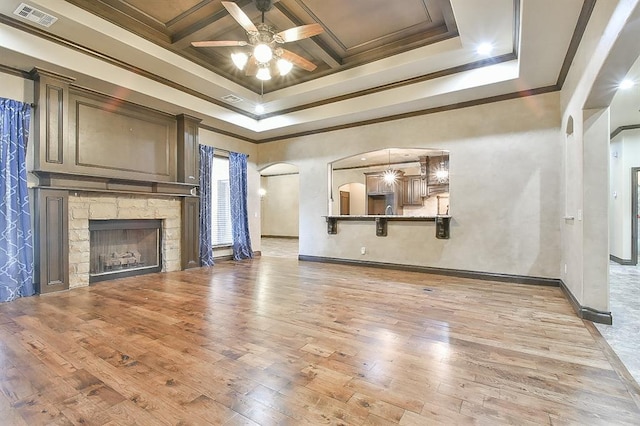 unfurnished living room featuring arched walkways, light wood-style flooring, a fireplace, coffered ceiling, and visible vents