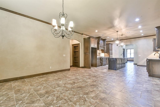 kitchen featuring dark brown cabinetry, a center island with sink, arched walkways, hanging light fixtures, and a notable chandelier