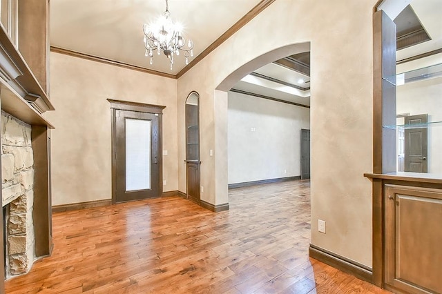 foyer with baseboards, arched walkways, ornamental molding, light wood-type flooring, and a chandelier