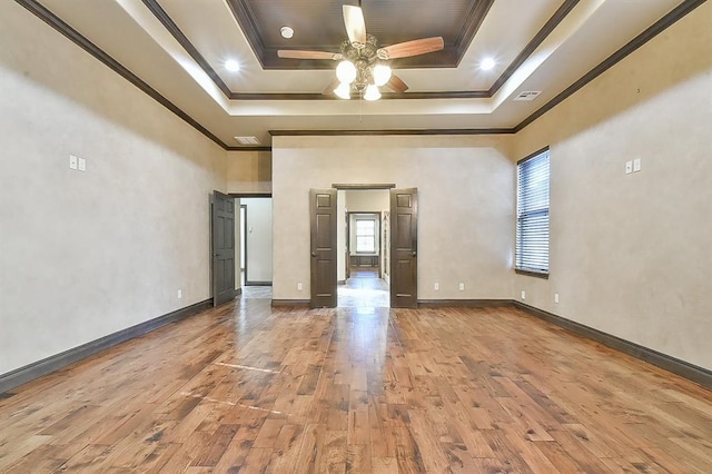 unfurnished bedroom with wood finished floors, ornamental molding, a raised ceiling, and baseboards