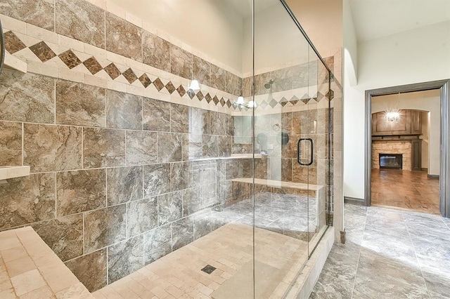 bathroom featuring a towering ceiling, a stall shower, and a glass covered fireplace