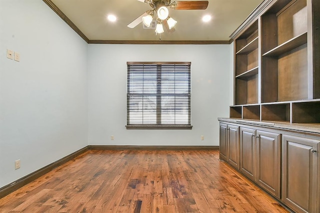 empty room with dark wood finished floors, crown molding, and baseboards