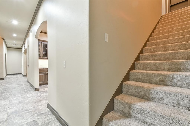 stairway featuring baseboards, arched walkways, and recessed lighting