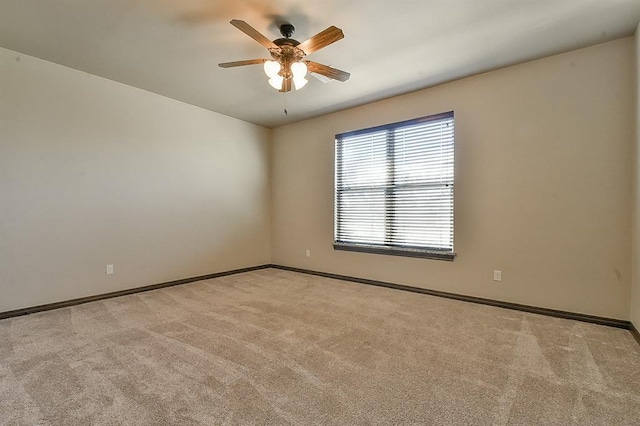 unfurnished room with a ceiling fan, light carpet, and baseboards