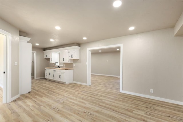 kitchen featuring light wood-type flooring, white cabinetry, and sink