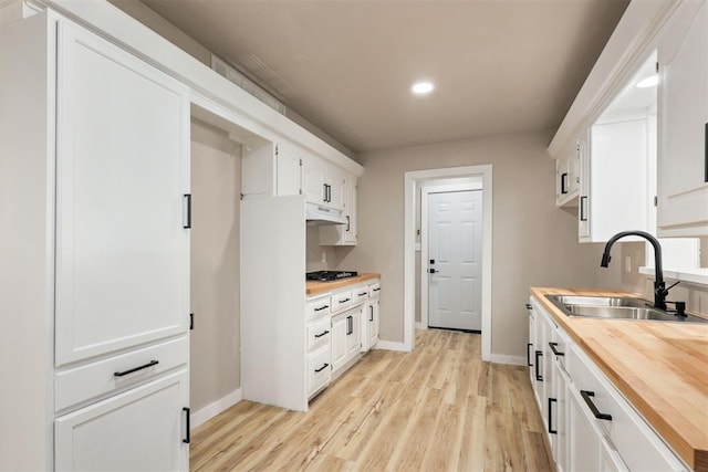 kitchen with white cabinetry, sink, stainless steel gas cooktop, butcher block countertops, and light hardwood / wood-style floors