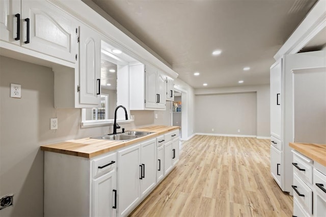 kitchen with white cabinets, butcher block countertops, and sink