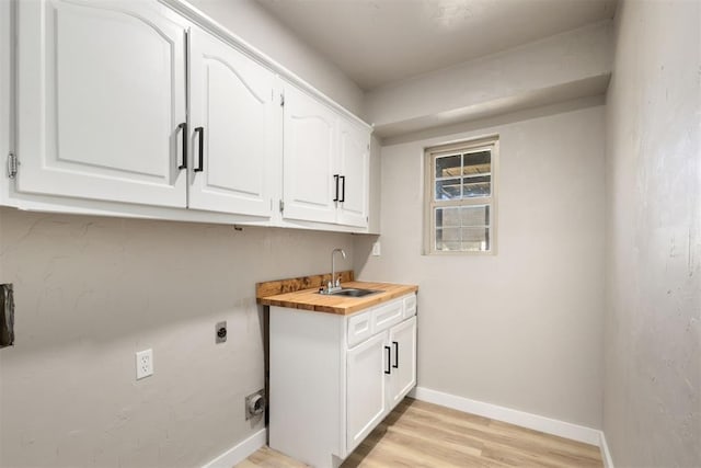 washroom featuring hookup for an electric dryer, cabinets, light wood-type flooring, and sink