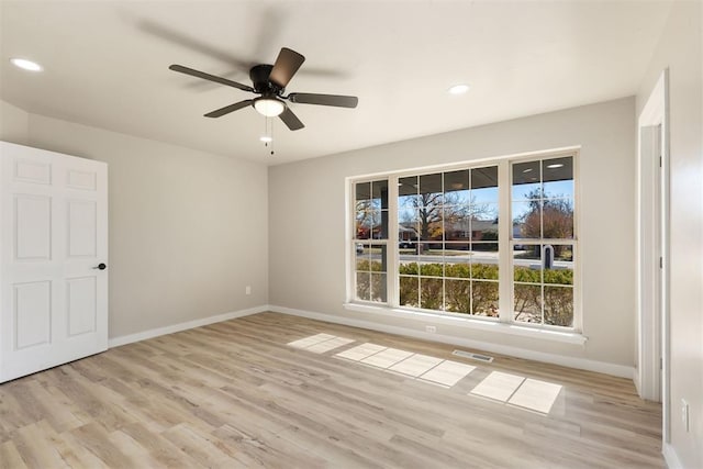 empty room with ceiling fan and light hardwood / wood-style flooring