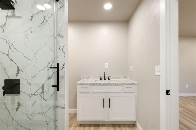 bathroom featuring hardwood / wood-style floors, vanity, and a tile shower