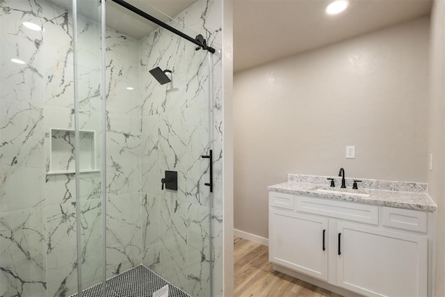 bathroom with hardwood / wood-style floors, vanity, and a shower with shower door