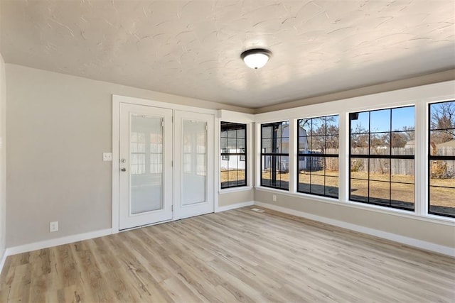 empty room with plenty of natural light and light hardwood / wood-style flooring