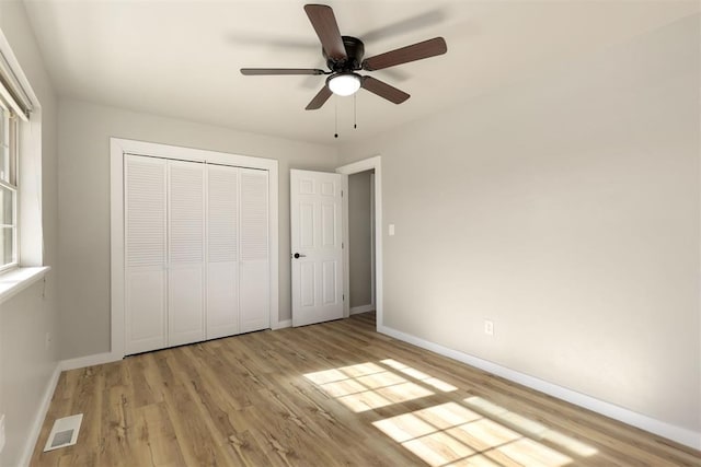 unfurnished bedroom with multiple windows, ceiling fan, a closet, and light wood-type flooring