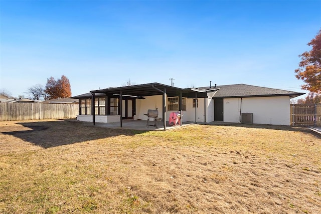 rear view of house featuring a patio area, a sunroom, a yard, and central AC unit