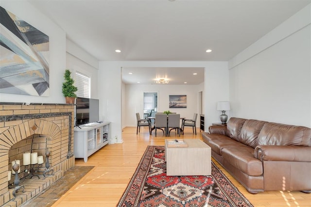 living room featuring wood-type flooring and a brick fireplace