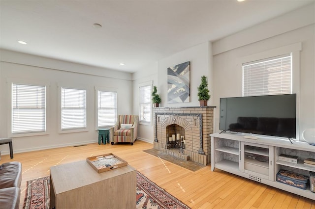 living room featuring wood-type flooring and a brick fireplace