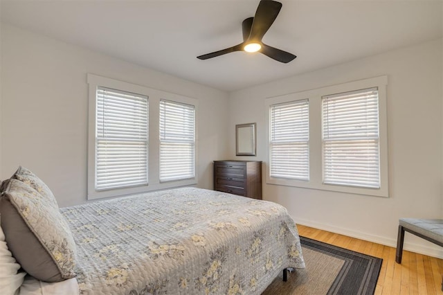 bedroom with multiple windows, ceiling fan, and hardwood / wood-style flooring