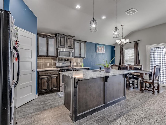 kitchen with a kitchen breakfast bar, dark brown cabinets, stainless steel appliances, and light wood-type flooring