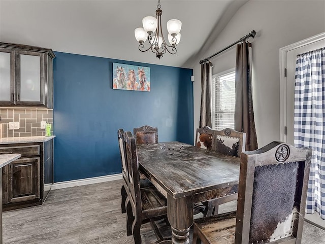 dining space featuring a notable chandelier, light hardwood / wood-style flooring, and vaulted ceiling