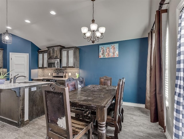 dining room with light hardwood / wood-style floors, a wealth of natural light, lofted ceiling, and sink