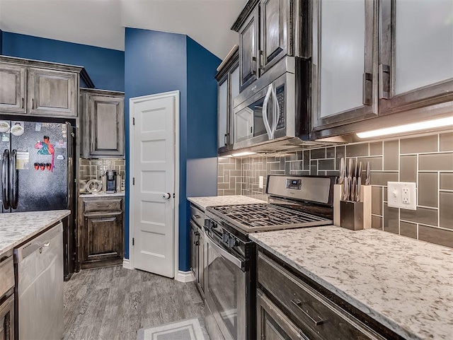 kitchen featuring dark brown cabinetry, decorative backsplash, light hardwood / wood-style flooring, and appliances with stainless steel finishes